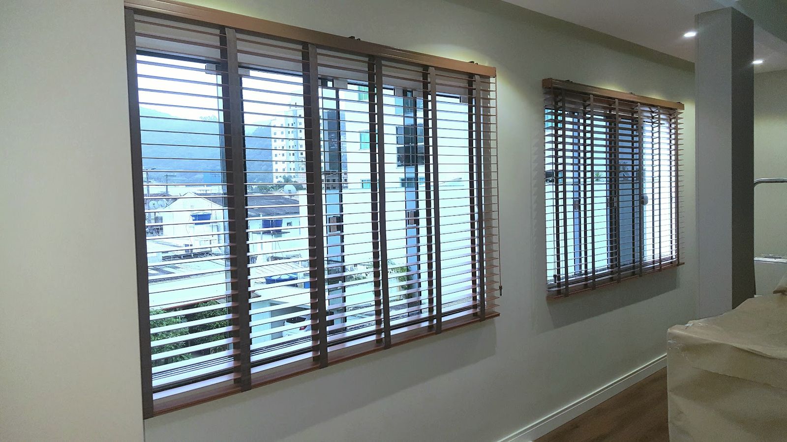 Persiana horizontal 50 mm em madeira com lâminas abertas e vista para as casas ao fundo