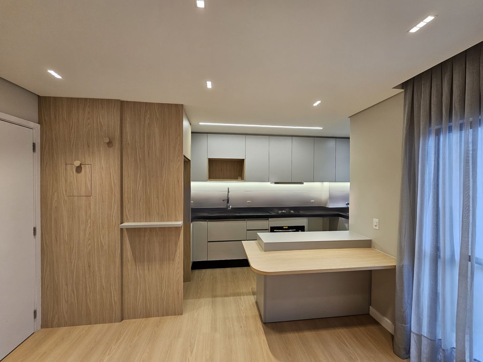 Cozinha planejada com painel de madeira e ilha fabricada pela Homelux
